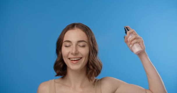Жінка розбризкує маску для волосся на голові. Використання жіночої косметики. Процедури догляду за красою на синьому екрані, 4k Ціни HQ — стокове відео