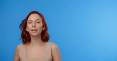 Kızıl saçlı güzel kadın mavi ekrandaki güzellik videosunda poz veriyor. Model fotoşopta saçlarını uzatıyor. 4k Prores Merkezi