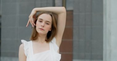Young dancer in white dress dances on the stairs of the theatre in slow motion, balerina does dance steps and pa outdoors, 4k 120 fps Prores HQ