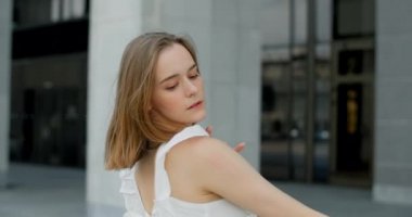 360 camera shot: young dancer in white dress dances on the stairs of the theatre in slow motion, balerina does dance steps and pa outdoors, 4k 120 fps Prores HQ