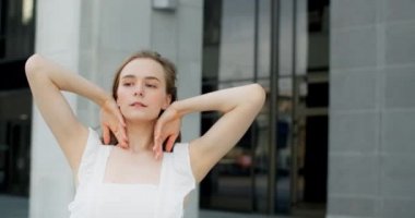 Young dancer in white dress dances on the stairs of the theatre in slow motion, balerina does dance steps and pa outdoors, 4k 120 fps Prores HQ