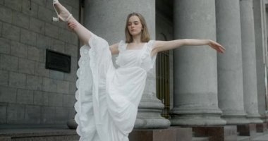 Young dancer in white dress dances on the stairs of the theatre in slow motion, balerina does dance steps and pa outdoors, 4k 120 fps Prores HQ