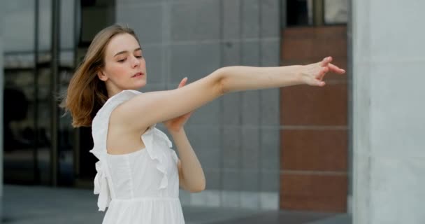 Young balerina in white dress whirls in the gallery of columns architectural complex in slow motion, balerina dances outdoors, 4k 120 fps Prores HQ — Stock videók