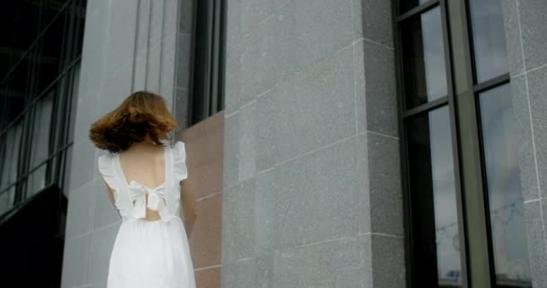 Young balerina in white dress whirls in the gallery of columns architectural complex in slow motion, balerina dances outdoors, 4k 120 fps Prores HQ — Stok video