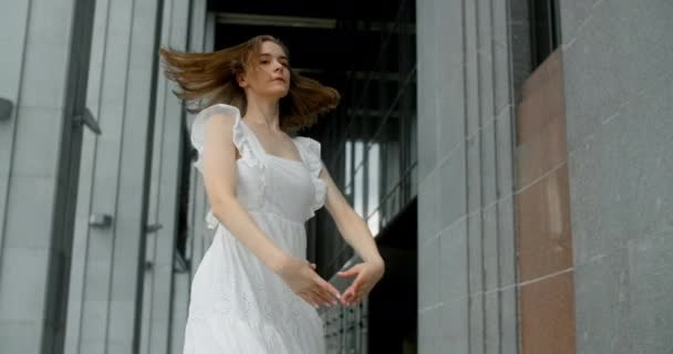 遅い動きで列の建築複合体のギャラリーで白いドレスの渦の若いバレリーナ、バレリーナは屋外で踊り、 4k 120 fps｜Prores HQ — ストック動画
