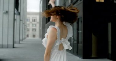 Young dancer woman in white dress whirls in the gallery of columns architectural complex in slow motion, balerina dances outdoors, 4k 120 fps Prores HQ