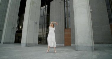 Young dancer in white dress dances in the gallery of columns architectural complex in slow motion, balerina does dance steps and pa outdoors, 4k 120 fps Prores HQ