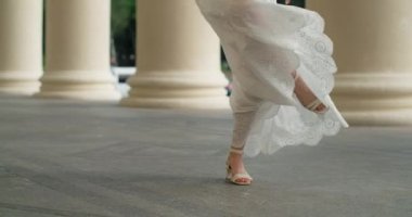 Legs of woman dancer in white long dress dancing outdoors in slow motion between the colums of the building, 4k 60p Prores HQ