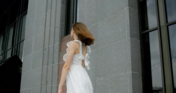 Young balerina in white dress whirls in the gallery of columns architectural complex in slow motion, balerina dances outdoors, 4k 120 fps Prores HQ — Vídeo de stock