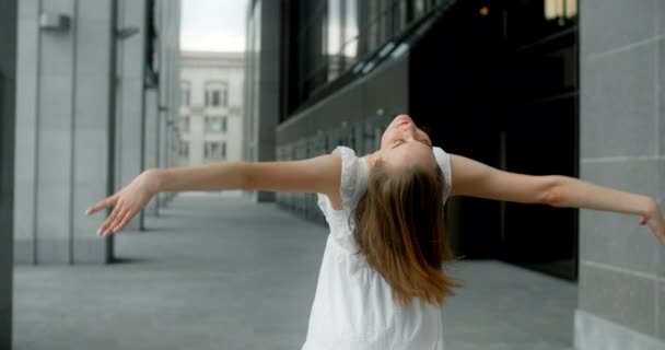 Young balerina in white dress runs through the gallery of columns in architectural complex in slow motion, balerina dances outdoors, 4k 120 fps Prores HQ — Vídeo de stock