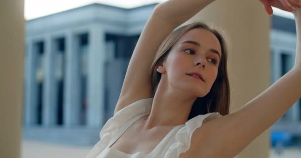 Young dancer in white dress dances on the stairs of the theatre in slow motion, balerina does dance steps and pa outdoors, 4k 120 fps Prores HQ — Stok video