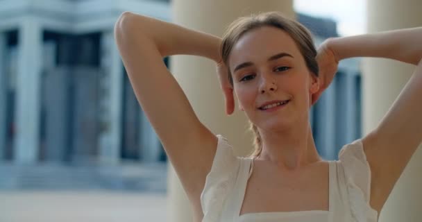 Young dancer in white dress dances on the stairs of the theatre in slow motion, balerina does dance steps and pa outdoors, 4k 120 fps Prores HQ — Stock video