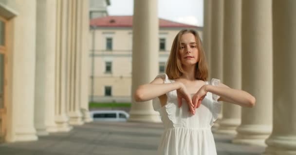 Young dancer woman in white dress whirls in the gallery of columns architectural complex in slow motion, balerina dances outdoors, 4k 120 fps Prores HQ — Video Stock
