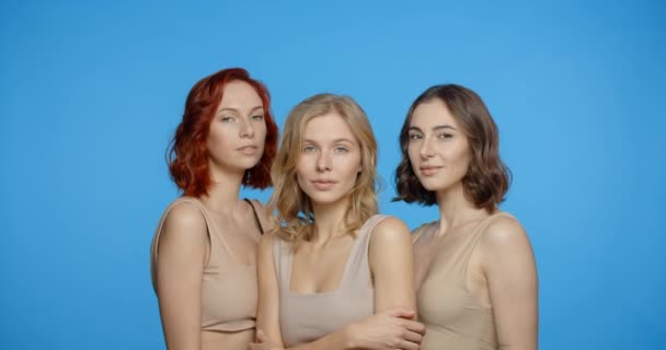 Blonde, redhead and dark haired woman are looking and smiling to the camera, portrait of different types of women in the blue screen, 4k 24p Prores — Αρχείο Βίντεο