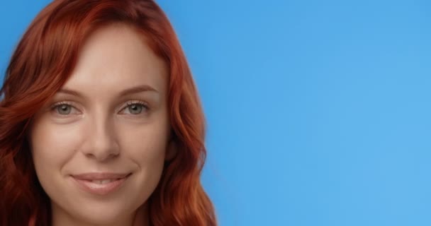 Redhead woman puts drop of face cream to the tip of her nose and laughs. Womens cosmetics usage. Beauty care procedures on blue screen, 4k Prores HQ — Wideo stockowe
