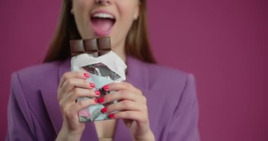 Happy young woman bites full chocolate bar in slow motion, 4k 60p Prores