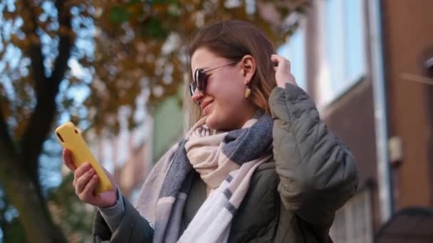 Woman have a talk by smartphone sitting on the bench in the street of old town, 4k 60p — Stockvideo