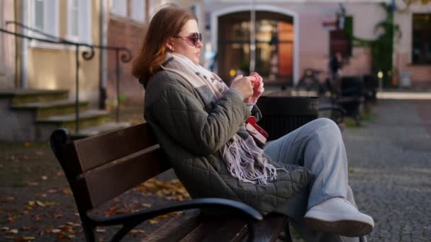 Woman have a talk by smartphone sitting on the bench in the street of old town, 4k 60p — Stock video