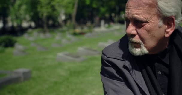 Triste vieil homme aux cheveux gris assis sur la tombe au cimetière, tristesse et tristesse au sujet de la perte de personnes proches, 4k 60p Prores — Video