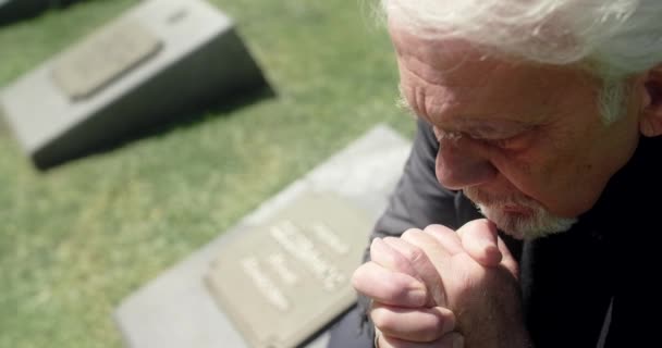 Smutný šedovlasý muž se modlí na hrobě na hřbitově. Smutek a smutek. Náboženství muž, 4k 60p Prores — Stock video