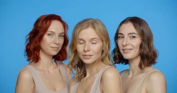 金发、红头发和黑头发的女人看着摄像机，微笑着，在蓝色的屏幕上，不同类型的女人的肖像，4k 24p Prores — 图库视频影像