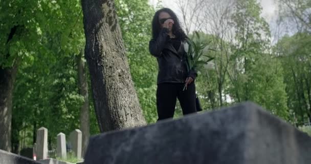 Retrato da mulher negra triste em óculos de sol em pé com flor no cemitério. Funeral e adeus, honrando os parentes passados. 4k 60p Prores — Vídeo de Stock
