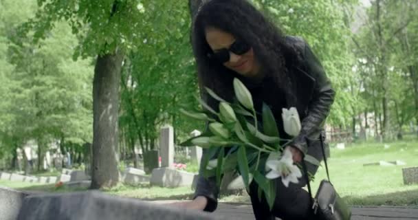 La mujer negra pone flores en la tumba y la acaricia. Griving en el cementerio, 4k 60p Prores — Vídeo de stock