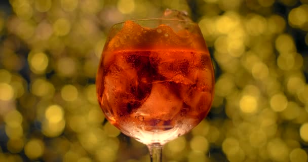 Aperol spritz cocktail met ijs. Bubbels van de besprenkelde drank in het glas, 4k 120fps Prores HQ — Stockvideo