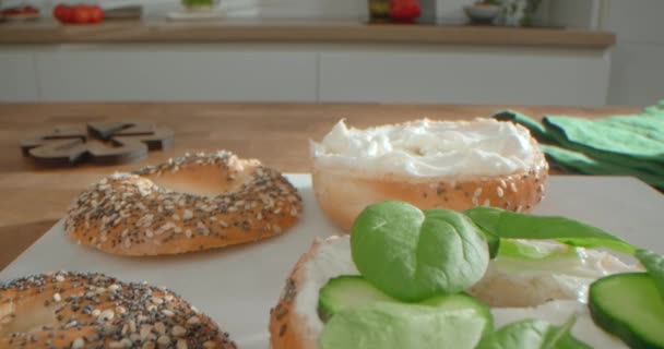 Mulher cozinha bagels com queijo cottage, salada e salame na cozinha da casa, 4k 60p Prores — Vídeo de Stock