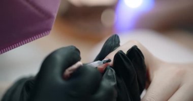 Manikürcü, kuaför, kozmetoloji ve güzellik işindeki müşterinin tırnaklarına jel süslemesi uygular. 4k Prores 60 peni.