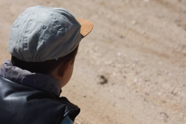 Sağında kopya alanı olan ailesiyle ormanda yürürken bir karınca kolonisini gözlemleyen tatlı çocuk.