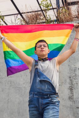 Neşeli çocuk, güneşli bir günde şehirde protesto için Igbt bayrağı sallıyor.