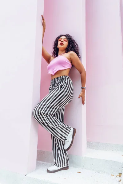 teen woman on pink background wall looking at camera posing fashion, artistic pink photo of woman posing.