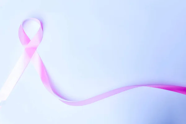 pink bow, pink ribbon symbol of fight against breast cancer isolated with space for text on blue background, international day of fight against cancer.