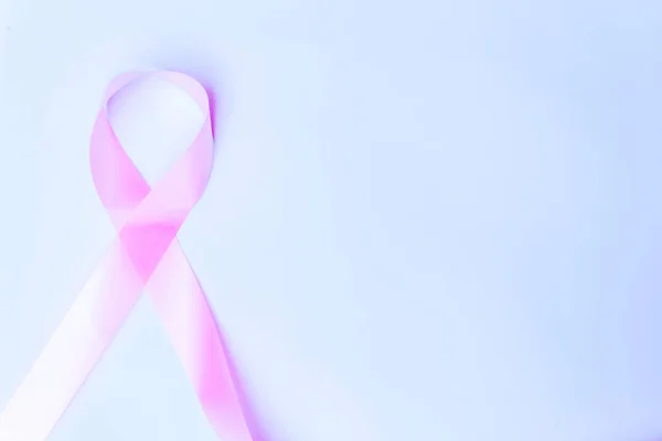 pink bow, pink ribbon symbol of fight against breast cancer isolated with space for text on blue background, international day of fight against cancer.