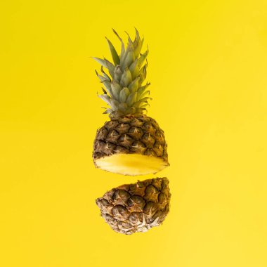 İki parçaya ayrılmış kahverengi ananas. Sarı arkaplanda minimum bileşim..
