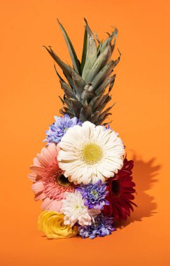 Parlak turuncu arka planda, çam ağacının üzerinde renkli çiçekler. En az yaratıcı kompozisyon fikri..