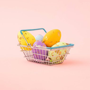 Pastel pembe arka planda renkli paskalya yumurtası dolu alışveriş sepeti. asgari yaratıcı kompozisyon.