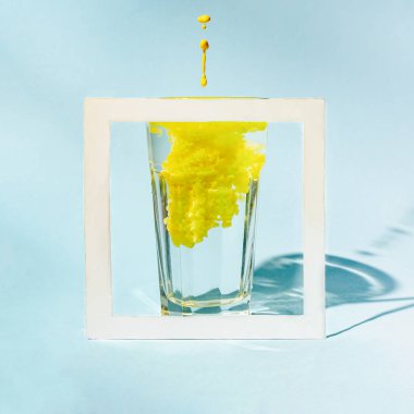 Mavi arkaplan üzerinde sarı renkli ve kopyalanmış su camının çok az yaratıcı bileşimi.