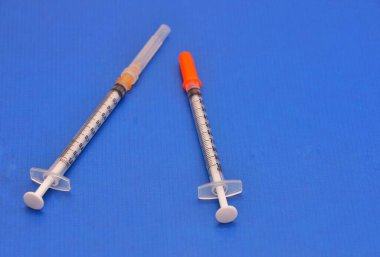 Deri içi enjeksiyonlar ve test dozları için kullanılan insülin şırıngası ve 1cc şırınga. Mavi arka planda izole edilmiş görüntü