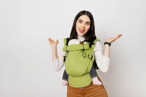 Bebek taşıyıcısında bebeği olan neşeli bir anne. 