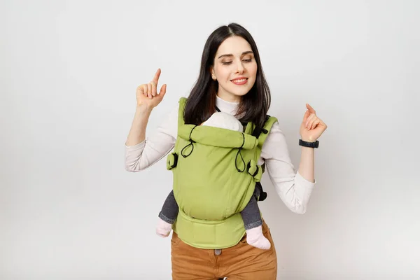 Yavru yeşil bir taşıyıcıda bebeği olan neşeli bir anne. 