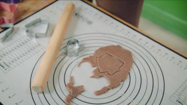 Genç beyaz kadın ev mutfağında hamurdan kurabiye kesiyor.