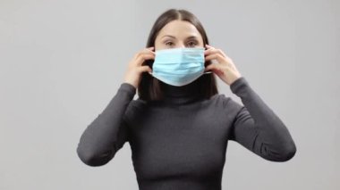 Gri kaplumbağa boyunlu kadın çok büyük bir maske taktı, salgın konsepti.
