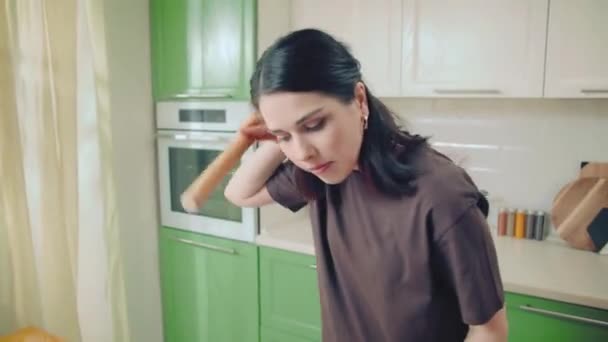 Молода біла жінка в коричневій футболці печиво для випічки на домашній кухні — стокове відео