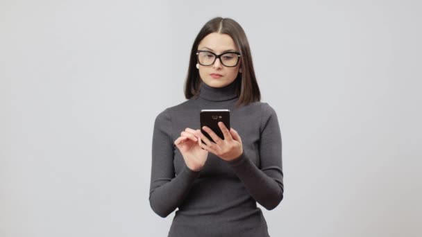 Mulher de óculos e vestido cinza em redes sociais serfing em seu telefone celular — Vídeo de Stock