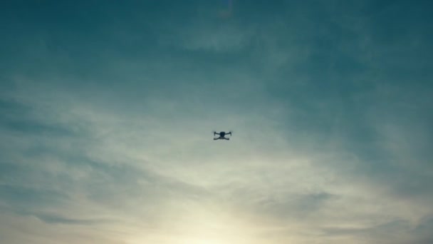 Wide shot of a flying drone silhouette on a sunset sky background — 비디오