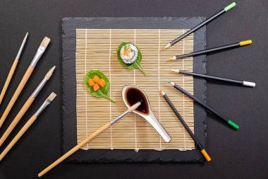 Japon yemek tabağı, suşi ve maki sunumu siyah zemin üzerinde fırça ve boya dekorasyonu ile.