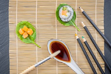 Japon yemek tabağı, suşi ve maki sunumu siyah zemin üzerinde fırça ve boya dekorasyonu ile.