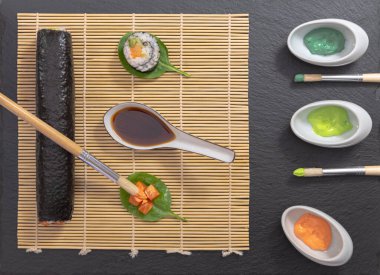 Japon yemek tabağı, suşi ve maki sunumu siyah zemin üzerinde fırça ve boya dekorasyonu ile.